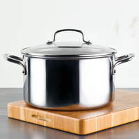 Stainless steel pot with a lid on a wooden cutting board.