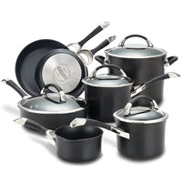 A set of black cookware pots and pans with lids on display.