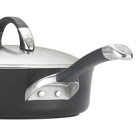 A close-up of a black saucepan with metal handles and a glass lid.