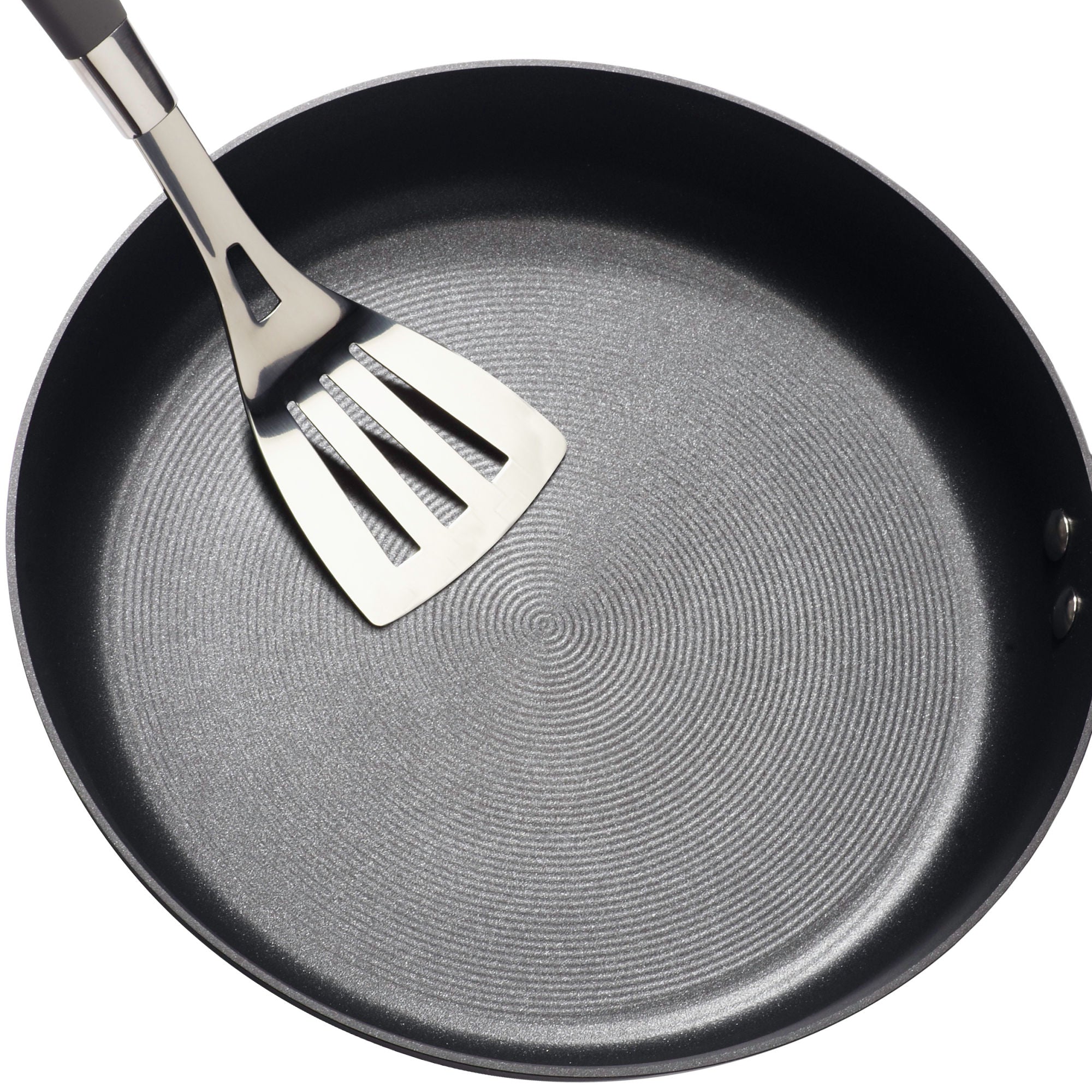 A stainless steel spatula resting in a non-stick frying pan.