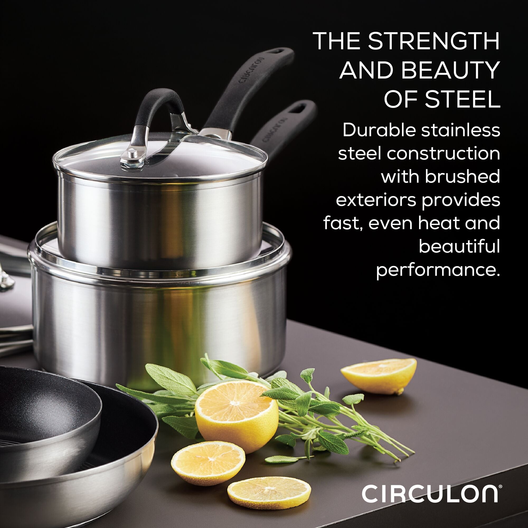 The 10-piece Hybrid Stainless Steel Cookware Set features a stylish arrangement of stacked stainless steel pots, accompanied by herbs and lemon halves, and is enhanced with SteelShield™ technology for added durability.