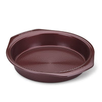 The 9-Inch Nonstick Round Cake Pan, featuring a round shape and brown color with raised handles, rests on a white background. Its oven-safe design and nonstick finish make it ideal for all your baking needs.