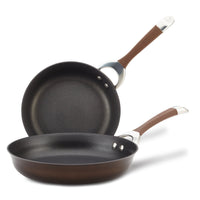 A pair of Hard-Anodized Frying Pan Set with a dependable nonstick system and elegant brown handles, stacked and tilted, ideal for any induction stovetop.