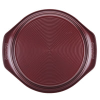 Nonstick, ridged-surface 9-inch round cake pan in dark maroon, featuring side handles for easy oven-safe baking.