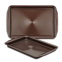 A set of two brown non-stick cookie pans, made from heavy gauge steel with textured surfaces, ensuring their oven safety and durability.