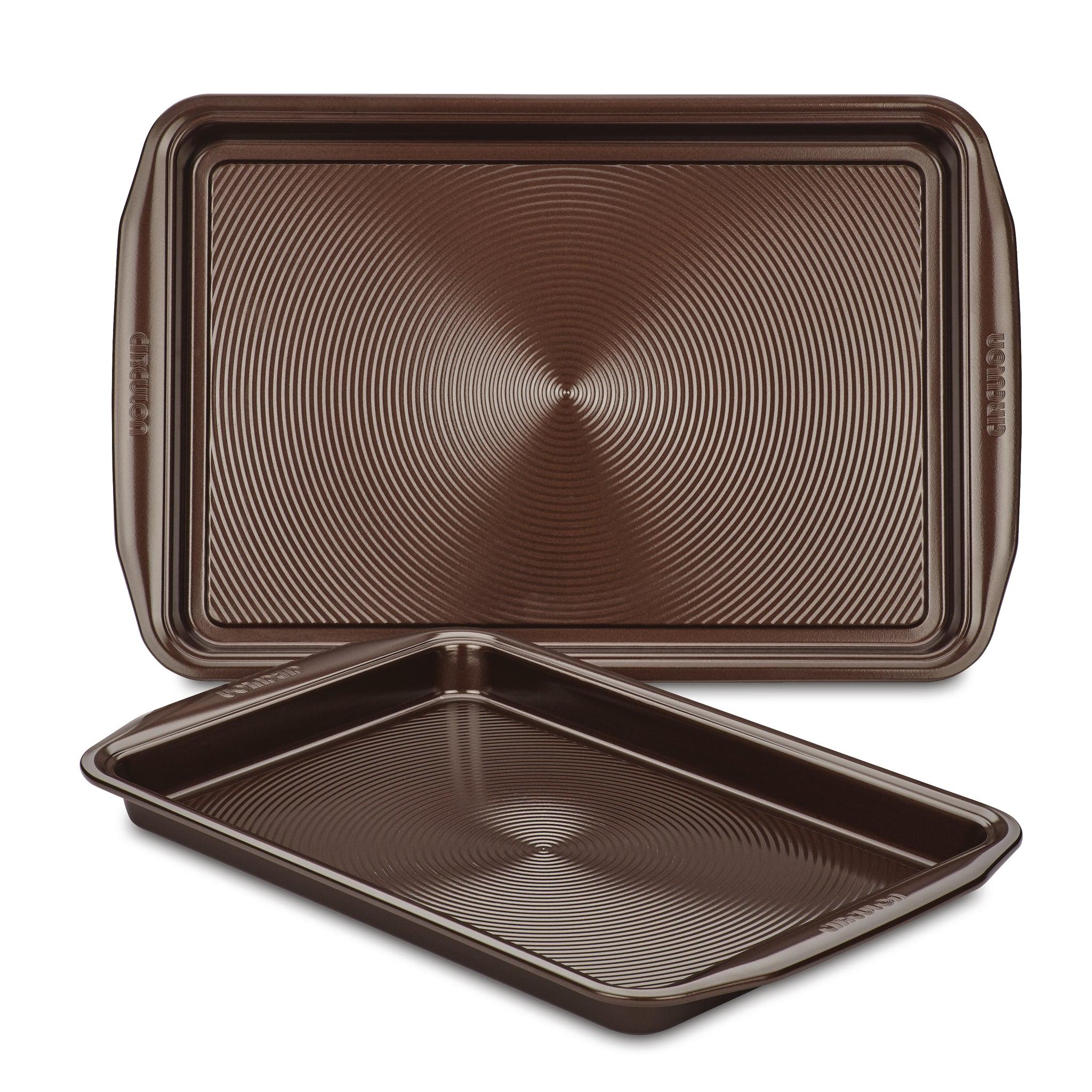 A set of two brown non-stick cookie pans, made from heavy gauge steel with textured surfaces, ensuring their oven safety and durability.