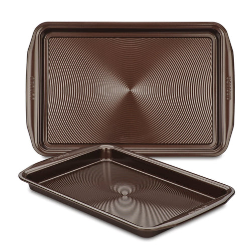 A set of two brown non-stick cookie pans, made from heavy gauge steel with textured surfaces, ensuring their oven safety and durability.
