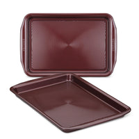 A pair of oven-safe, brown cookie sheets from the 2-Piece Nonstick Cookie Sheet Set, featuring textured surfaces and stacked together, ideal for your culinary creations.