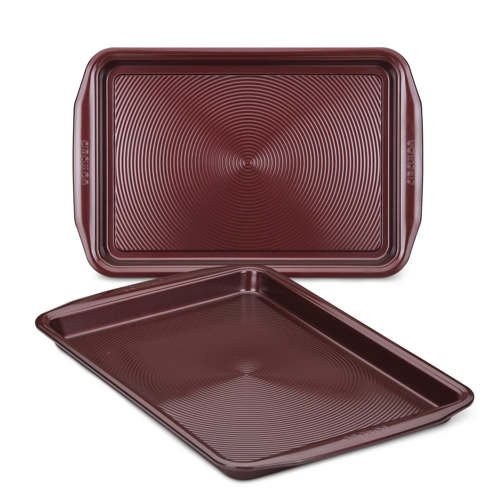 A pair of oven-safe, brown cookie sheets from the 2-Piece Nonstick Cookie Sheet Set, featuring textured surfaces and stacked together, ideal for your culinary creations.