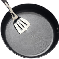 A metal spatula rests on an empty 8.5-inch nonstick frying pan, ready to showcase the TOTAL Nonstick System's superior performance.